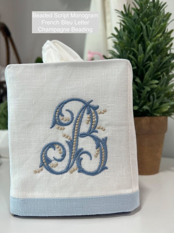 White linen tissue cover with baby blue edge trim and an embroidered beaded script monogram letter B in French bleu with champagne beading.